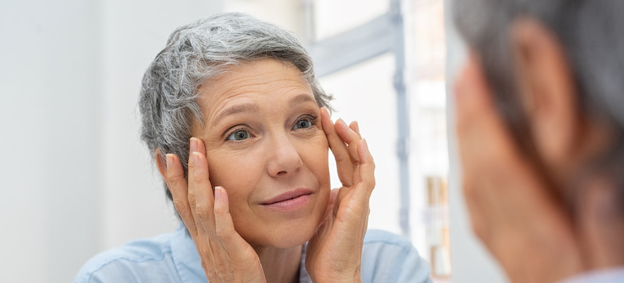 senior woman looking in the mirror at her eyes