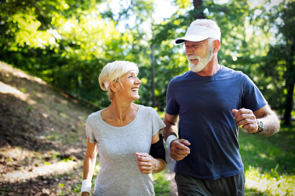 happy senior couple running on a trail