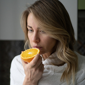 woman trying to smell an orange