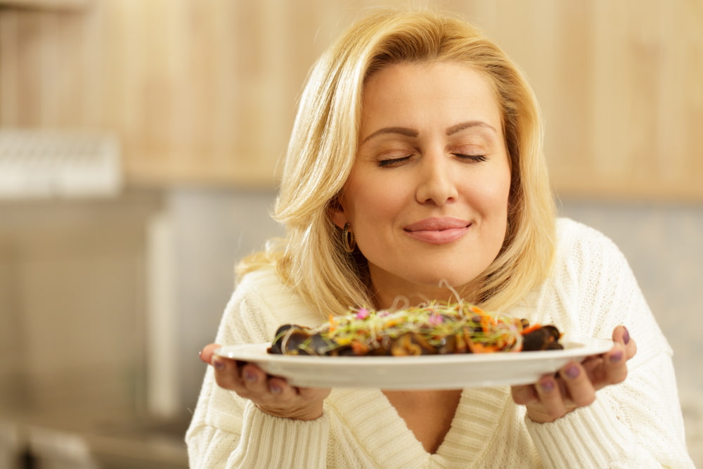 person smelling a plate of food and smiling