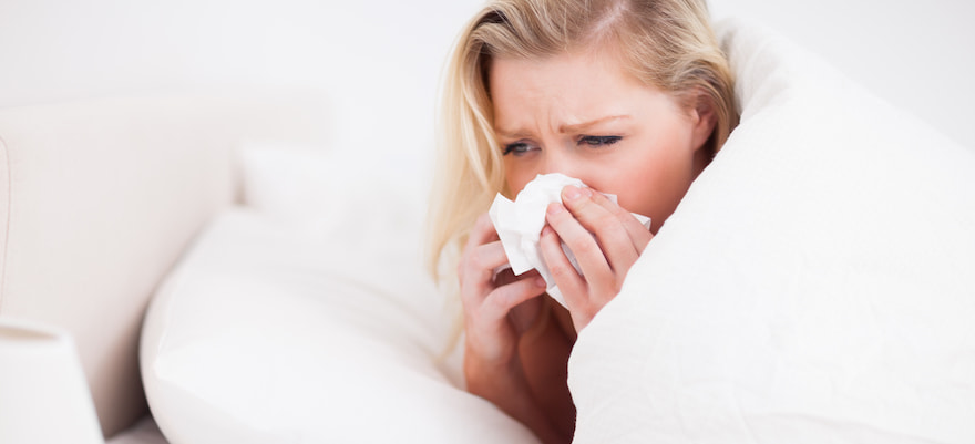 woman in bed blowing her nose