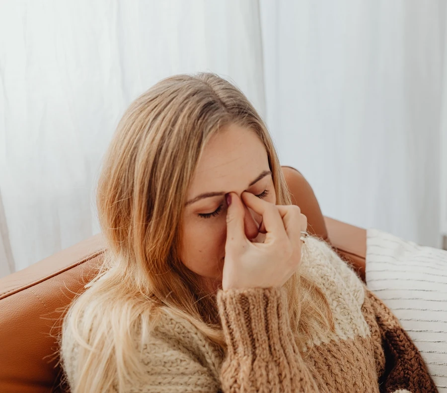 Woman holding the bridge of her nose in discomfort