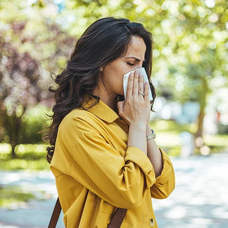 woman suffering from sinus and turbinate related symptoms, blowing her nose into a tissue